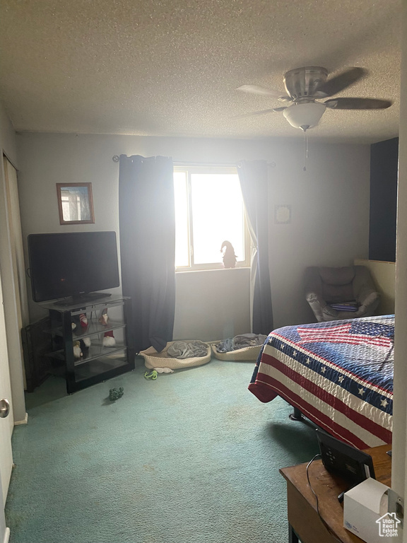 Carpeted bedroom featuring a textured ceiling and a ceiling fan