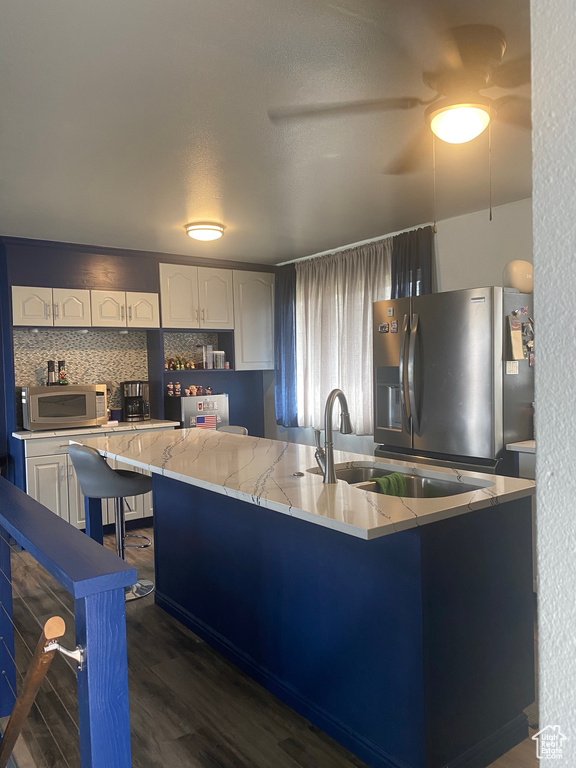 Kitchen featuring dark wood-type flooring, white cabinets, stainless steel appliances, and light stone countertops