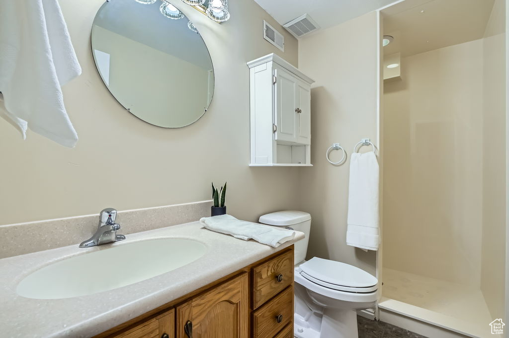 Bathroom featuring visible vents, toilet, vanity, and walk in shower