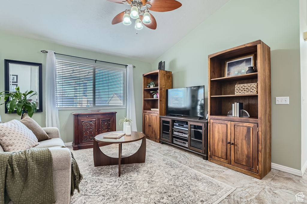 Living room featuring baseboards, vaulted ceiling, and a ceiling fan