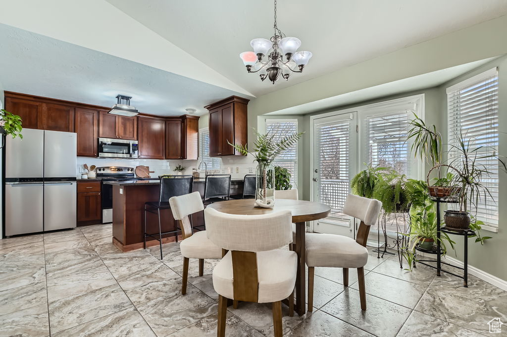 Dining area with baseboards, lofted ceiling, a chandelier, and marble finish floor