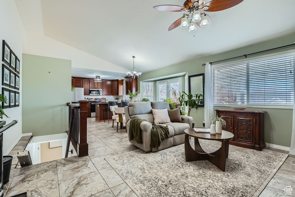 Living area with marble finish floor, ceiling fan with notable chandelier, lofted ceiling, and baseboards
