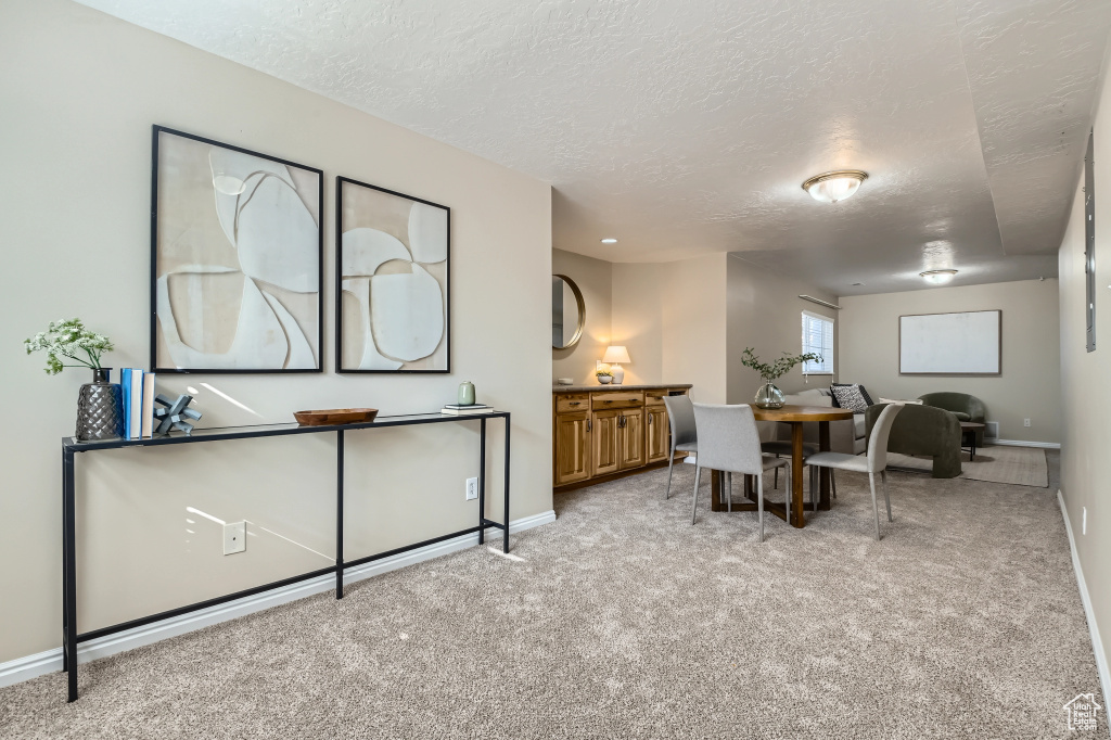 Home office with light carpet, baseboards, and a textured ceiling