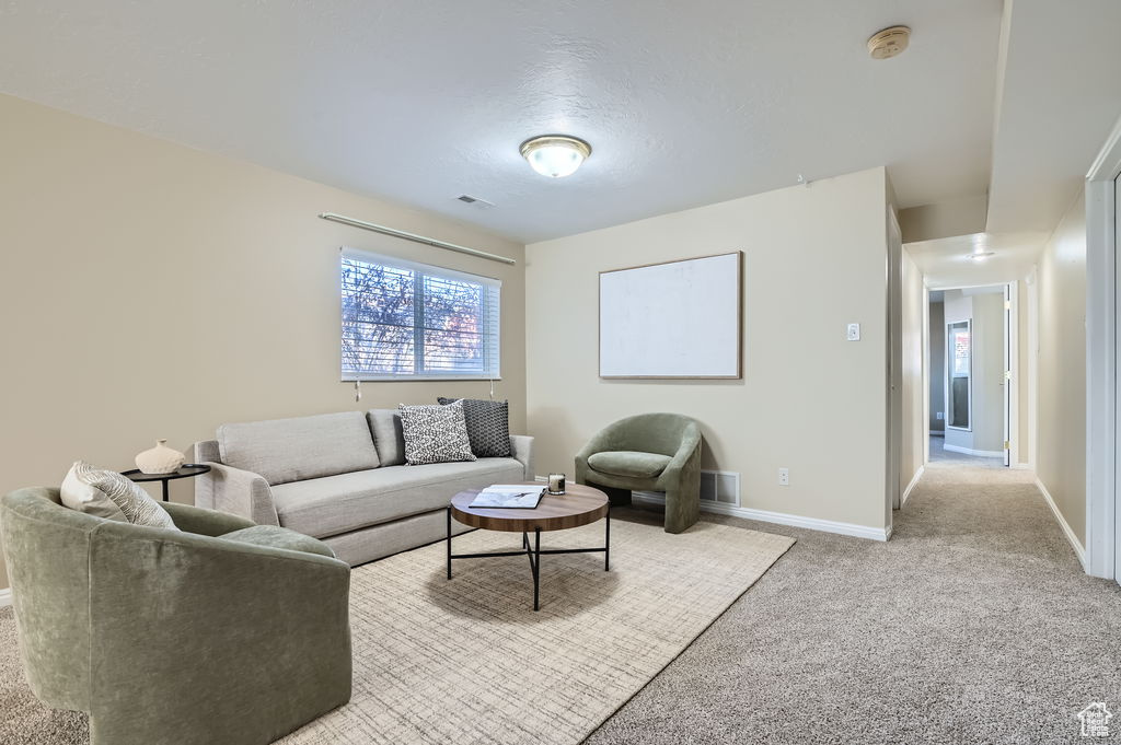 Living room featuring baseboards, visible vents, carpet floors, and a textured ceiling
