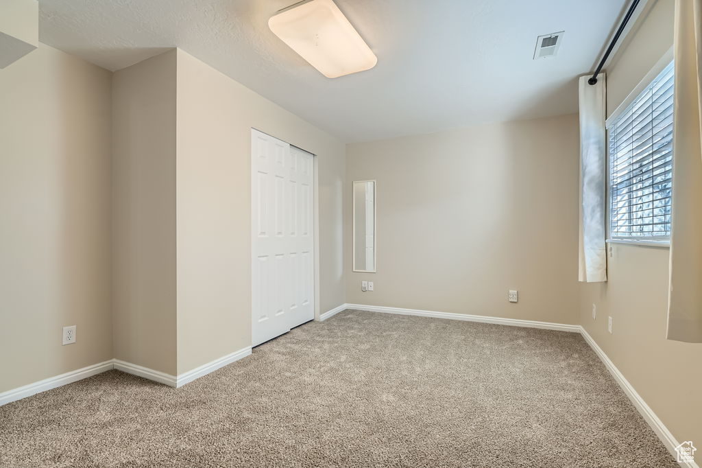 Unfurnished bedroom with baseboards, visible vents, a closet, and carpet