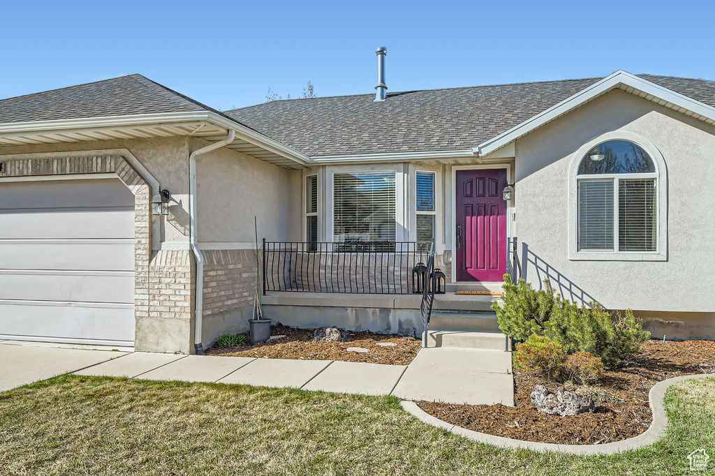 Single story home with stucco siding, a garage, and roof with shingles