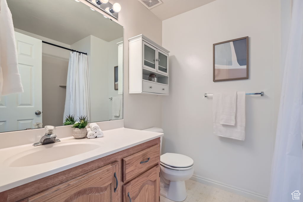 Bathroom featuring toilet, vanity, baseboards, and visible vents