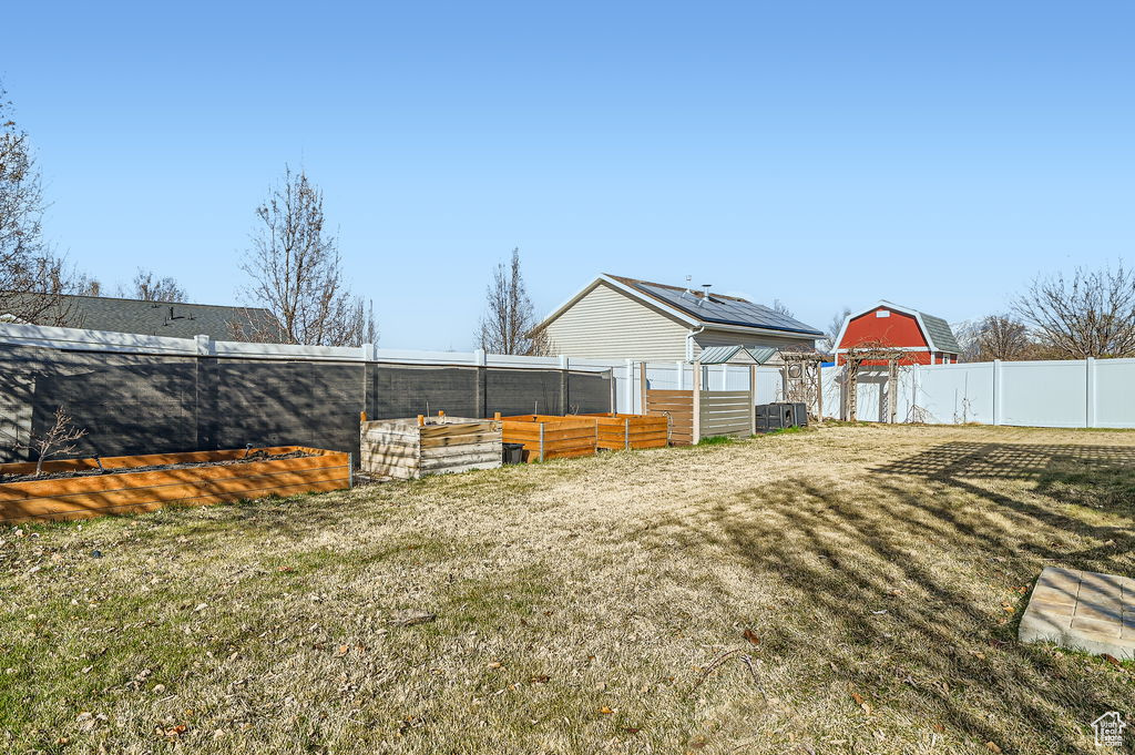 View of yard with fence private yard, an outdoor structure, and a vegetable garden