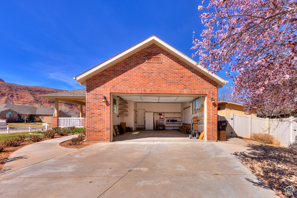 Exterior space featuring concrete driveway, fence, a gate, brick siding, and a garage