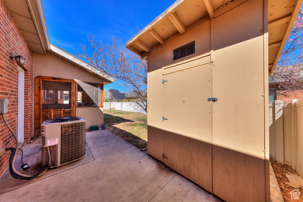 View of patio featuring an outbuilding, cooling unit, a shed, and a fenced backyard