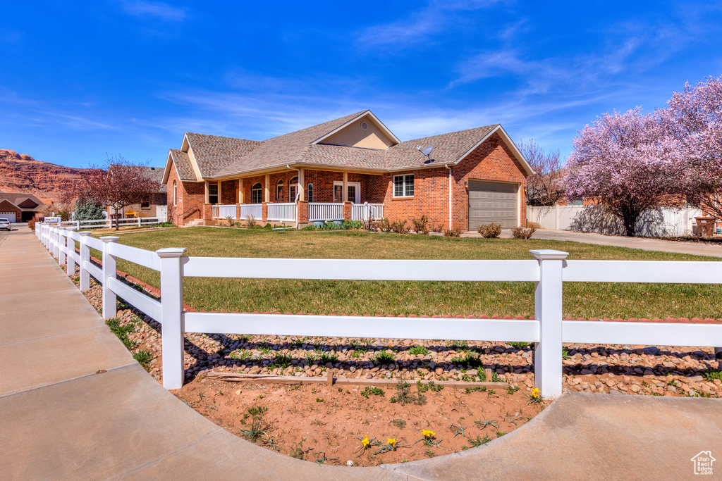 View of front of property featuring brick siding, a fenced front yard, a front yard, and a garage
