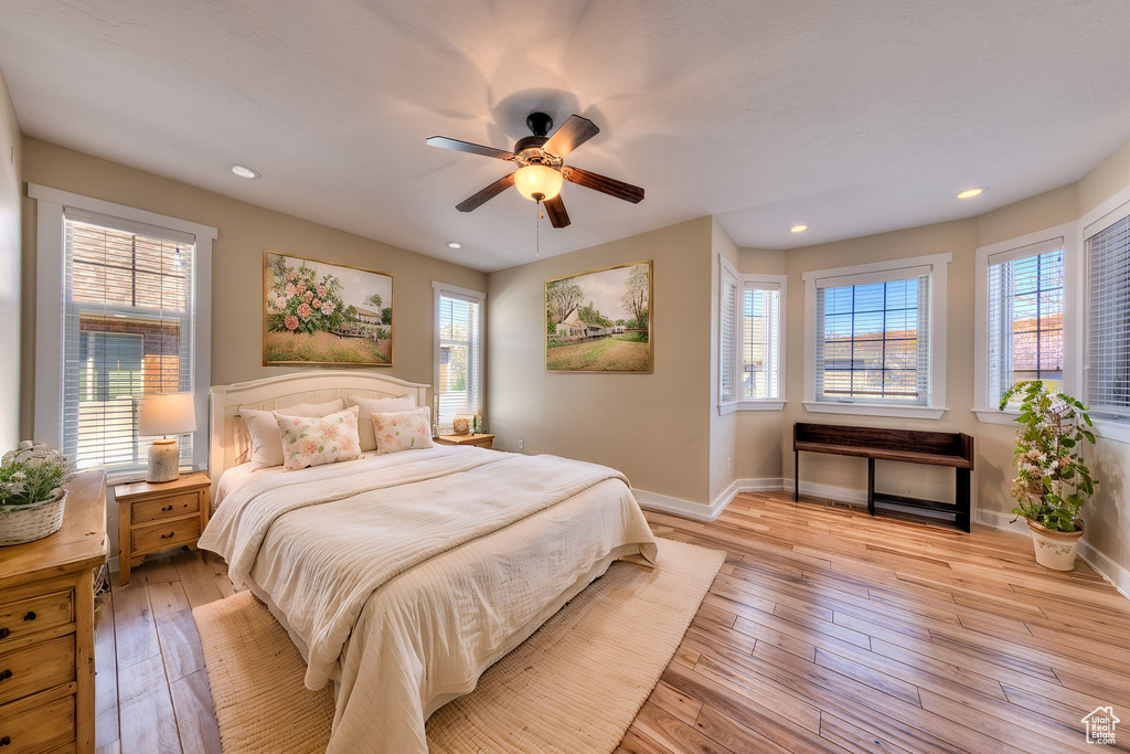 Bedroom with multiple windows, light wood-type flooring, and baseboards