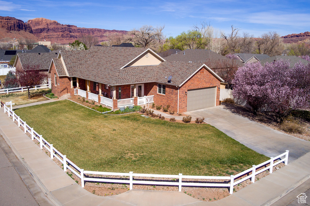 Ranch-style house with an attached garage, driveway, a front lawn, brick siding, and fence private yard