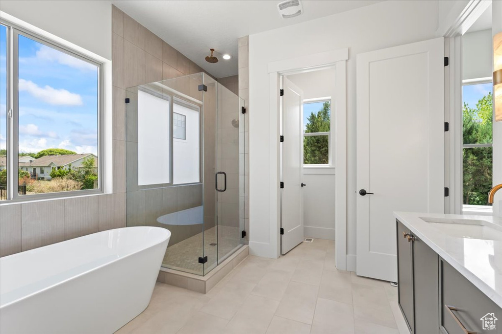 Full bathroom with a shower stall, tile patterned floors, a freestanding tub, and double vanity