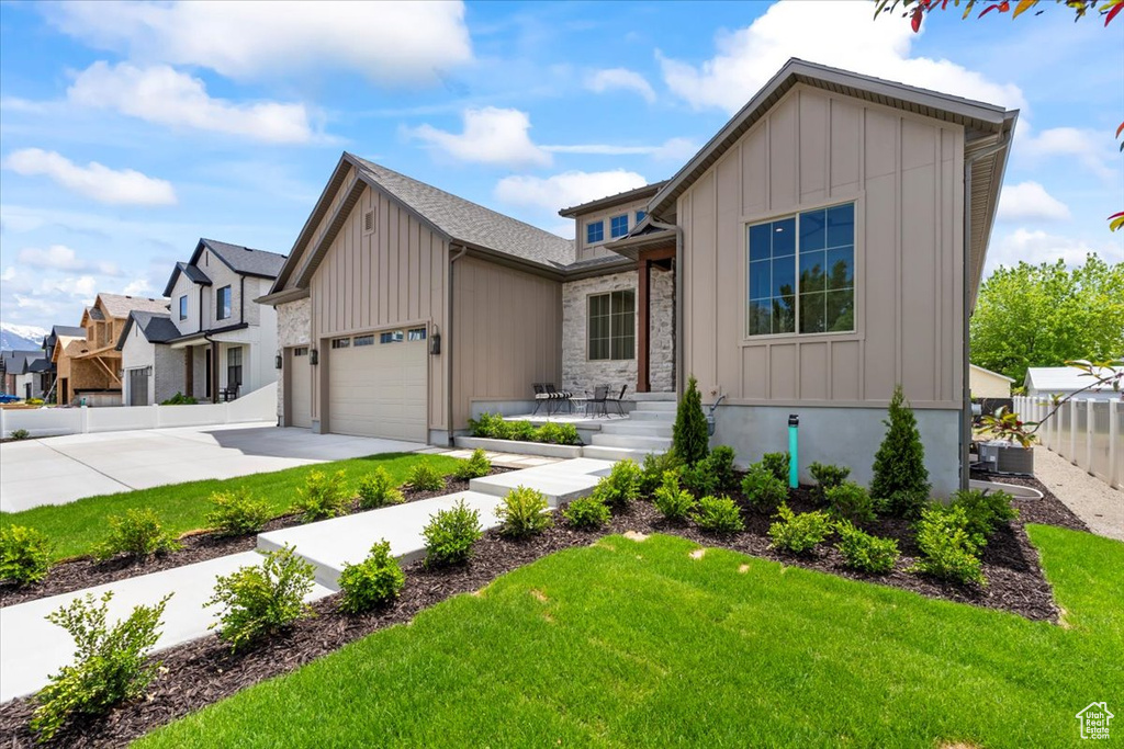 View of front facade featuring board and batten siding, driveway, an attached garage, and a residential view