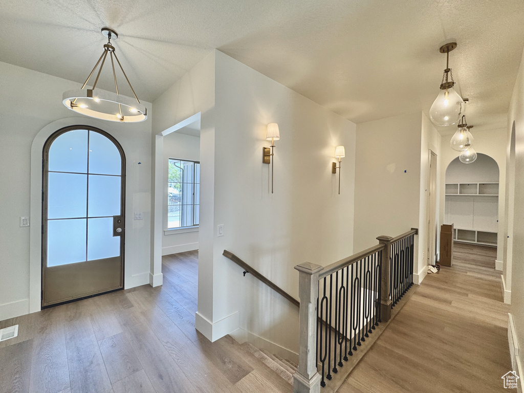Foyer entrance with wood finished floors, baseboards, and arched walkways