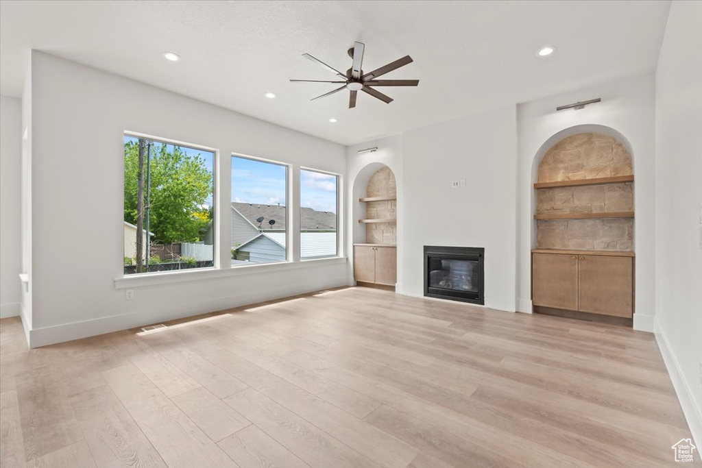 Unfurnished living room featuring a ceiling fan, a glass covered fireplace, baseboards, light wood-type flooring, and recessed lighting