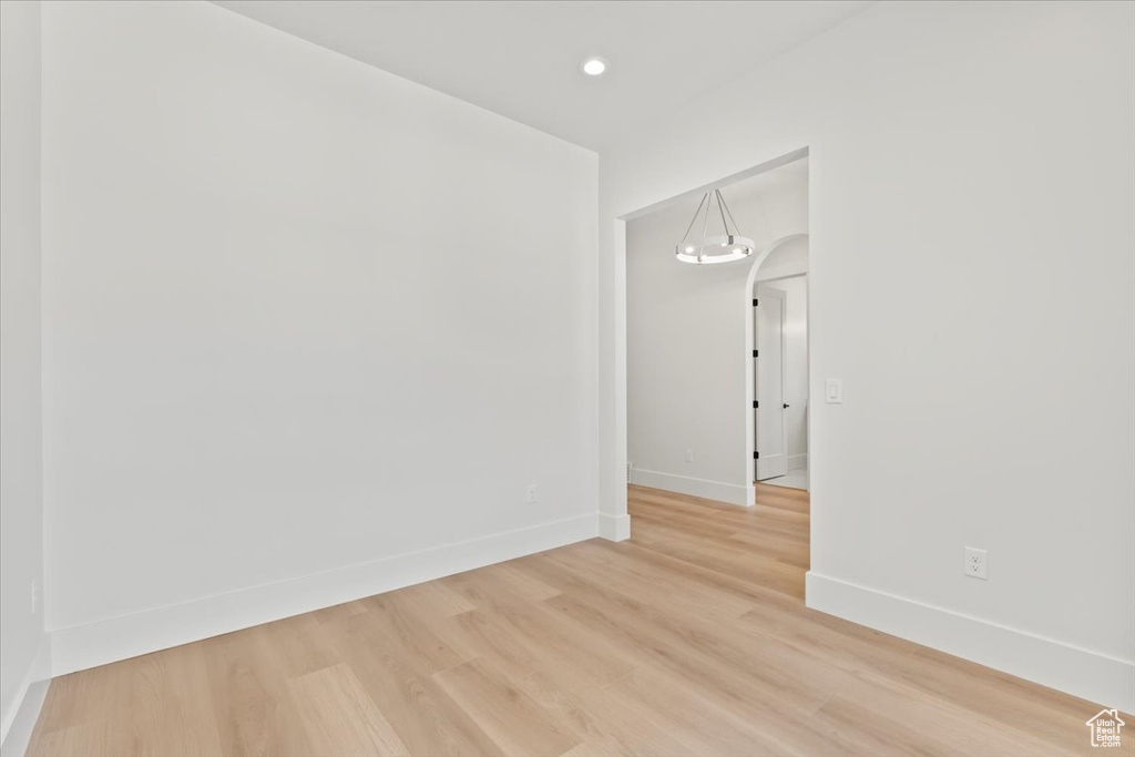 Spare room with arched walkways, baseboards, light wood finished floors, and recessed lighting