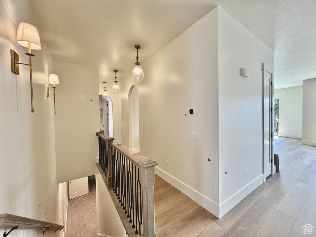 Hallway with light wood-style floors, an upstairs landing, and baseboards