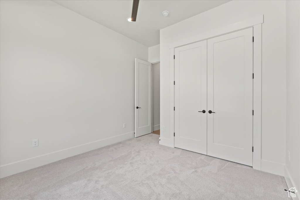 Unfurnished bedroom featuring light colored carpet, baseboards, and a closet