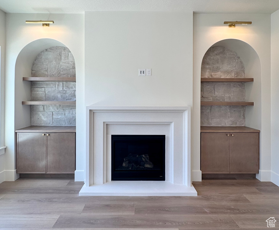 Detailed view of wood finished floors and a fireplace with raised hearth