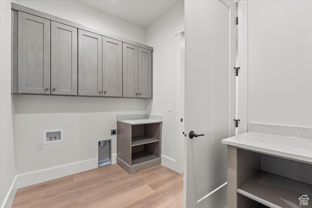 Laundry room featuring cabinet space, electric dryer hookup, light wood-style floors, hookup for a washing machine, and baseboards