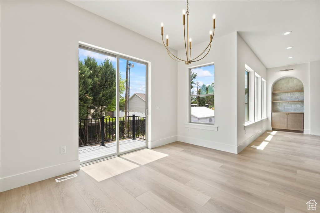Unfurnished dining area featuring a chandelier, healthy amount of natural light, wood finished floors, baseboards, and recessed lighting