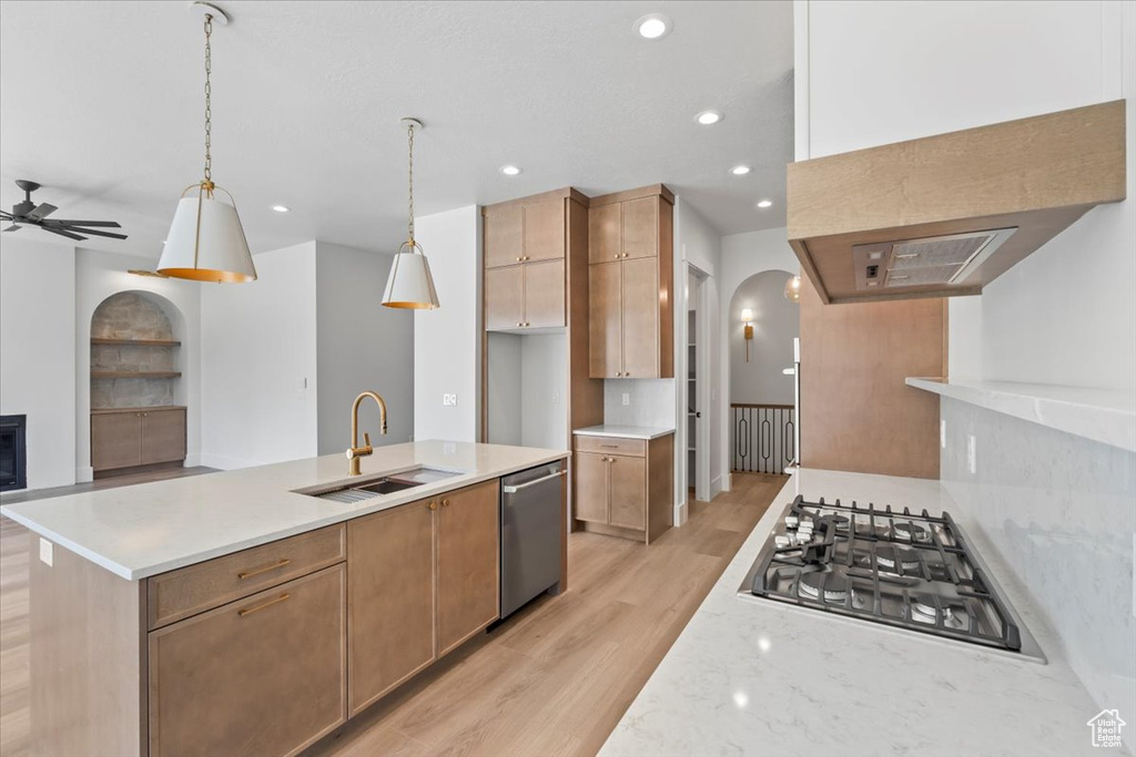 Kitchen featuring a sink, appliances with stainless steel finishes, arched walkways, light wood-style flooring, and recessed lighting