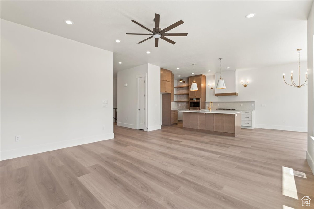 Unfurnished living room with recessed lighting, baseboards, light wood-type flooring, a ceiling fan, and a sink