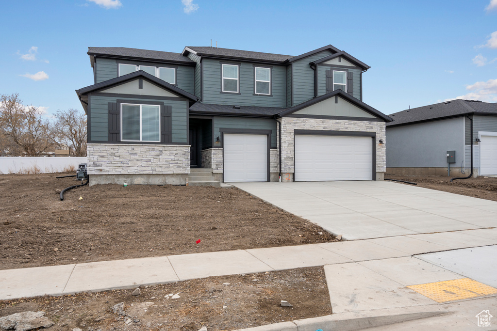 View of front facade with stone siding, concrete driveway, and a garage