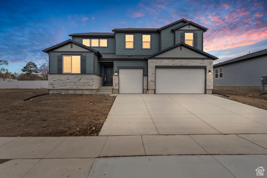 View of front of property with stone siding, driveway, and an attached garage