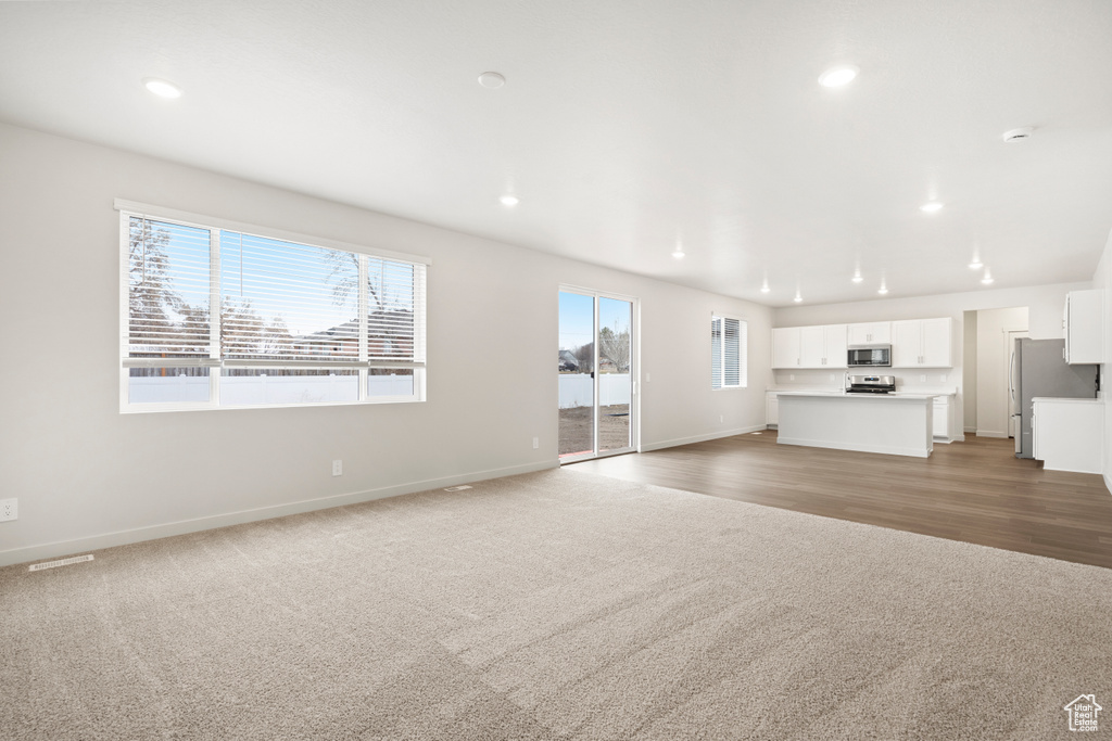 Unfurnished living room featuring light carpet, baseboards, and recessed lighting