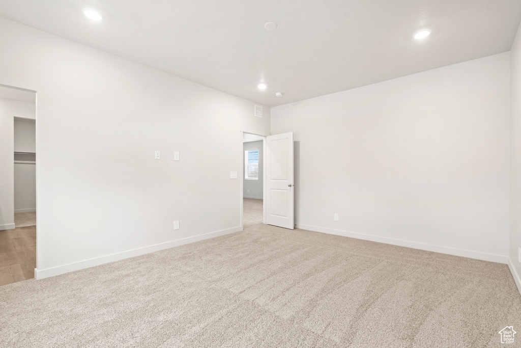 Unfurnished bedroom with recessed lighting, light carpet, baseboards, and a spacious closet