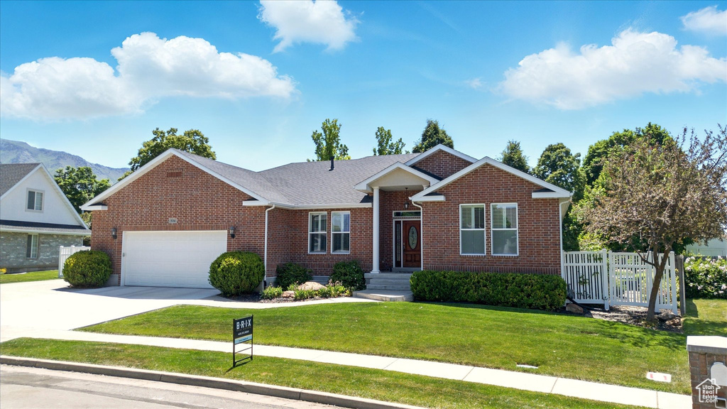 View of front facade featuring an attached garage, brick siding, driveway, and a mountain view