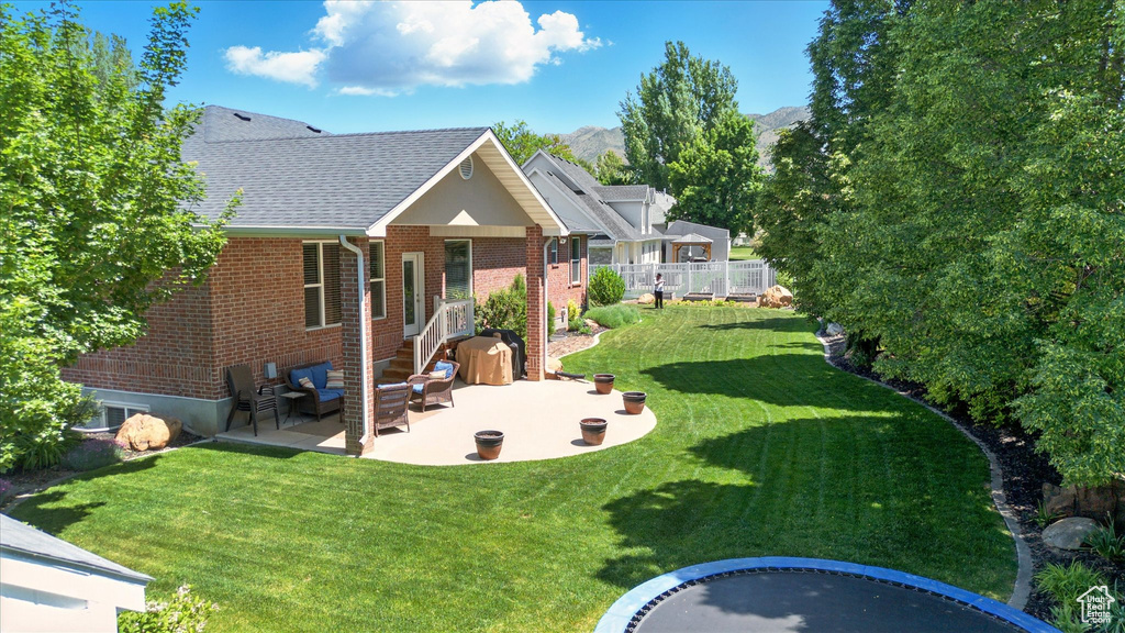 Rear view of property with a patio area, brick siding, a shingled roof, outdoor lounge area, and a mountain view