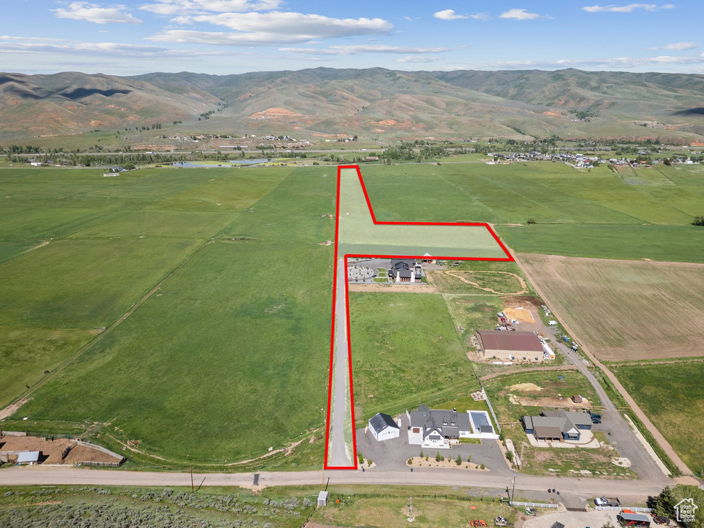Aerial view of property\'s location featuring property boundaries highlighted, rural landscape, and a mountain backdrop