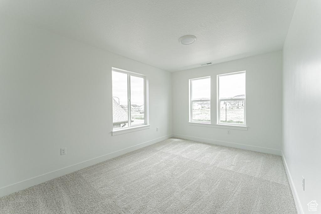 Spare room featuring light carpet and baseboards
