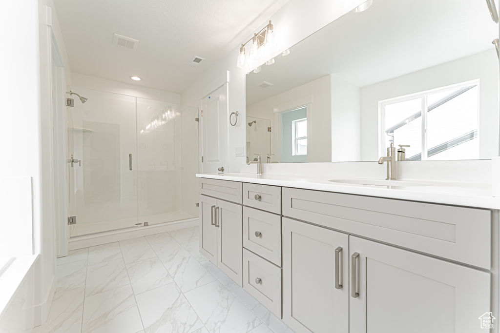 Bathroom with a shower stall, double vanity, marble finish flooring, and recessed lighting