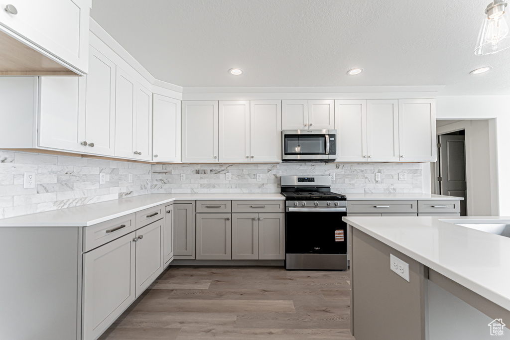Kitchen featuring appliances with stainless steel finishes, light countertops, light wood-style floors, recessed lighting, and tasteful backsplash