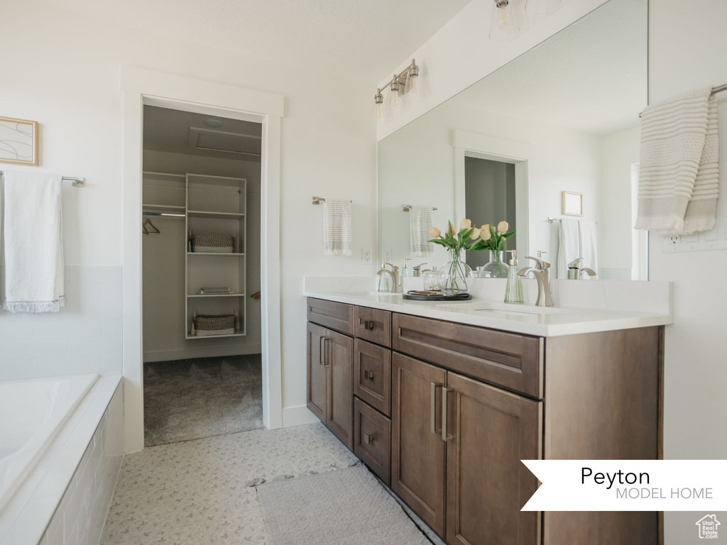 Full bath featuring a bath, double vanity, a sink, and a spacious closet