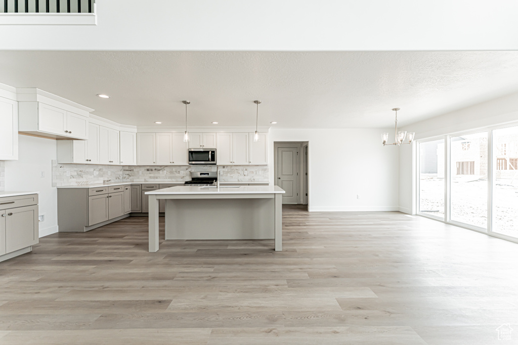 Kitchen with stainless steel appliances, a chandelier, tasteful backsplash, recessed lighting, and light wood finished floors
