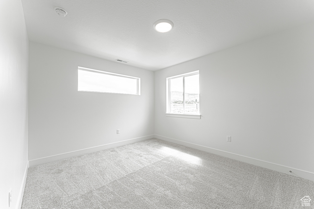 Carpeted empty room featuring a smoke detector and baseboards