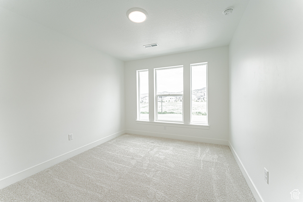 Unfurnished room featuring light carpet and a smoke detector