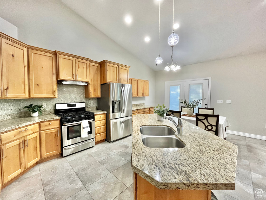 Kitchen featuring appliances with stainless steel finishes, under cabinet range hood, decorative backsplash, a kitchen island with sink, and high vaulted ceiling