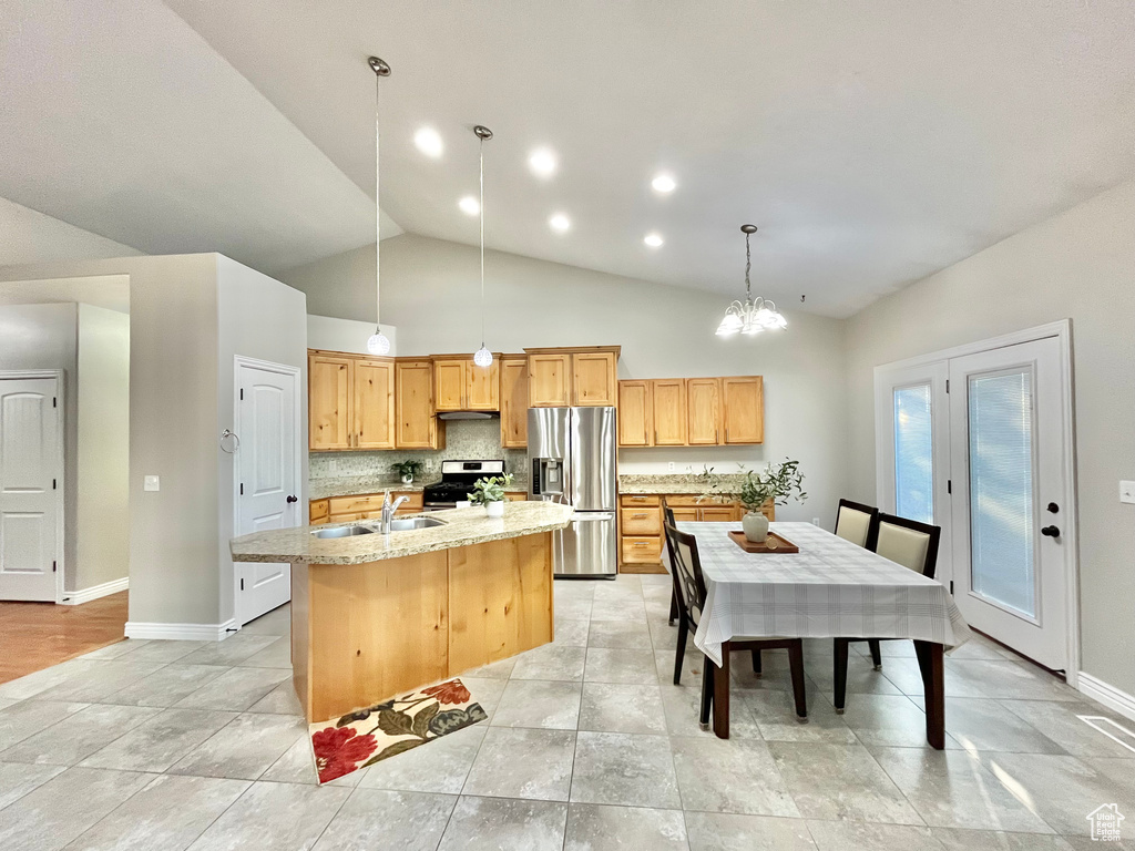 Kitchen featuring stainless steel appliances, a kitchen island with sink, vaulted ceiling, backsplash, and pendant lighting