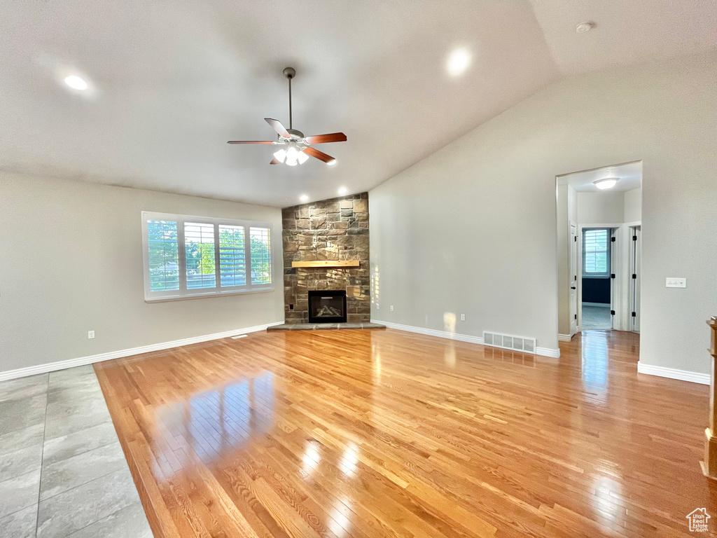 Unfurnished living room featuring a ceiling fan, healthy amount of natural light, light wood finished floors, vaulted ceiling, and recessed lighting