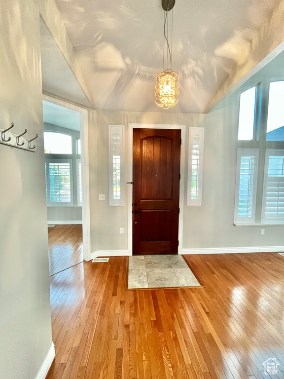 Entryway with wood-type flooring, vaulted ceiling, and a chandelier