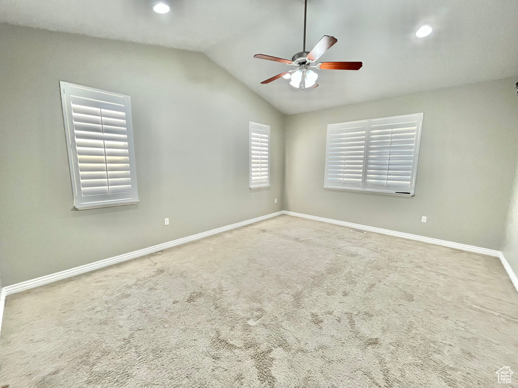Carpeted empty room with a ceiling fan, vaulted ceiling, and recessed lighting