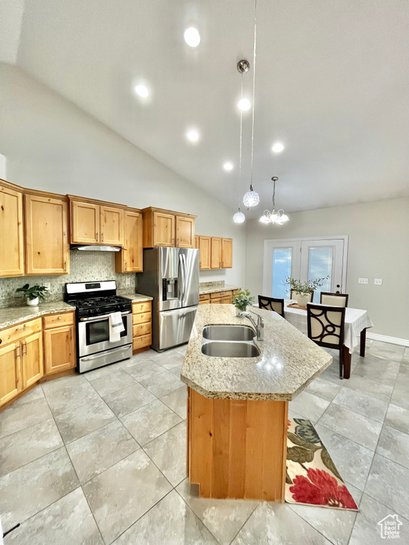 Kitchen with appliances with stainless steel finishes, decorative backsplash, decorative light fixtures, lofted ceiling, and a kitchen island with sink