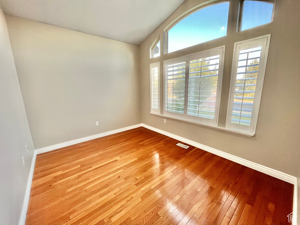 Spare room featuring plenty of natural light, hardwood / wood-style floors, and vaulted ceiling